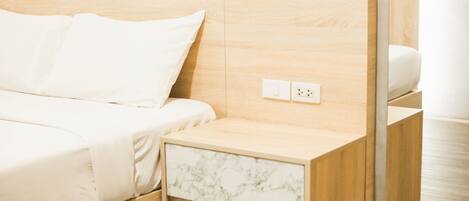A neatly made bed with white linens, a wooden headboard, and a nightstand with a marble drawer.