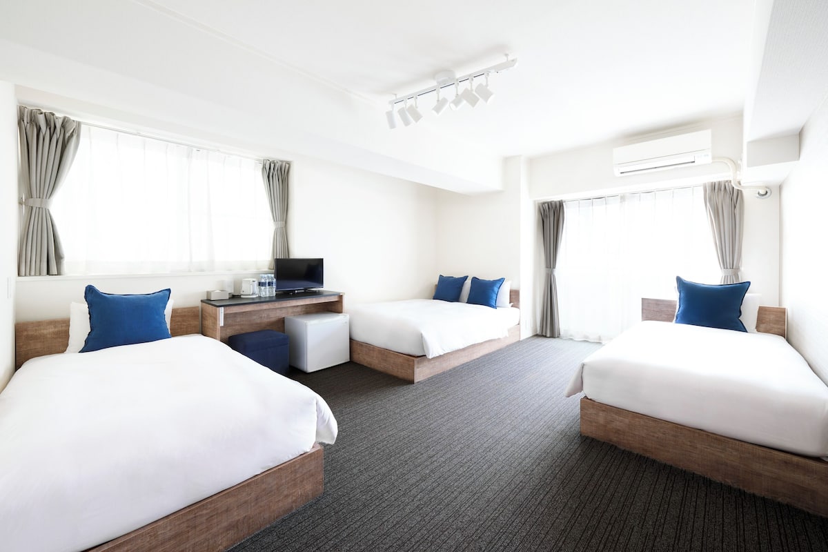 A hotel room with two beds, a desk, and a television.