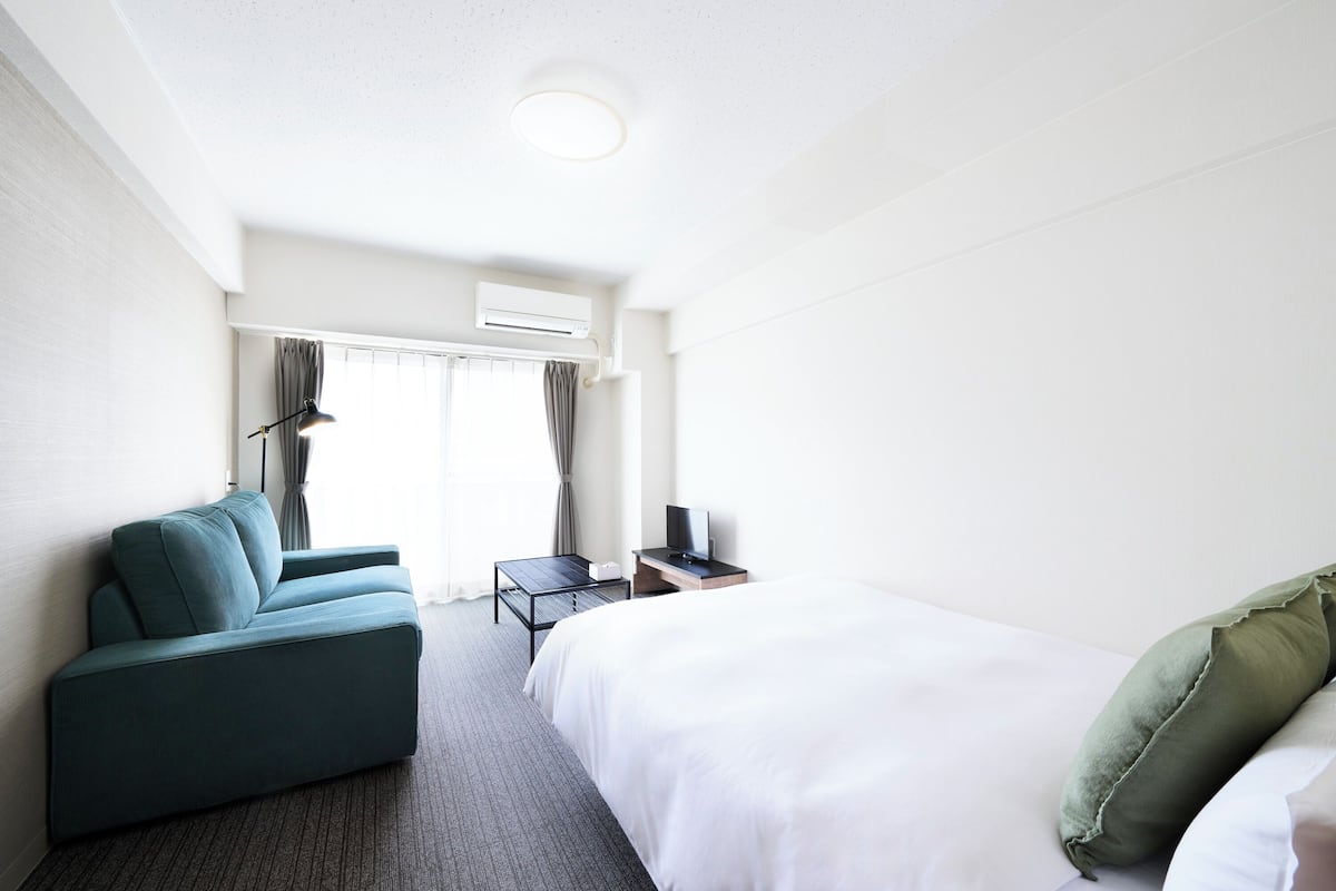 A hotel room with a bed, a sofa, a desk, and a chair.