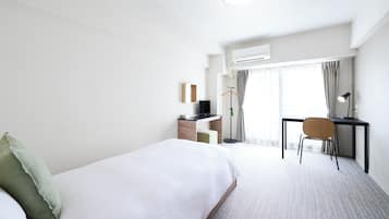 A hotel room with a bed, a desk, a chair, and a TV.
