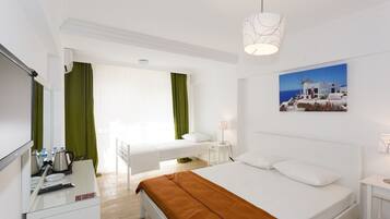 A hotel room with a bed, a desk, a chair, a lamp, a picture on the wall, and a window with curtains.