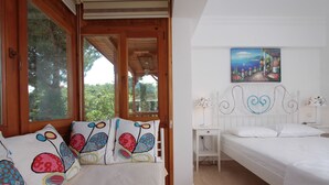 Une chambre avec deux lits, un plafond en bois, une table de chevet blanche et un tableau représentant un paysage côtier.