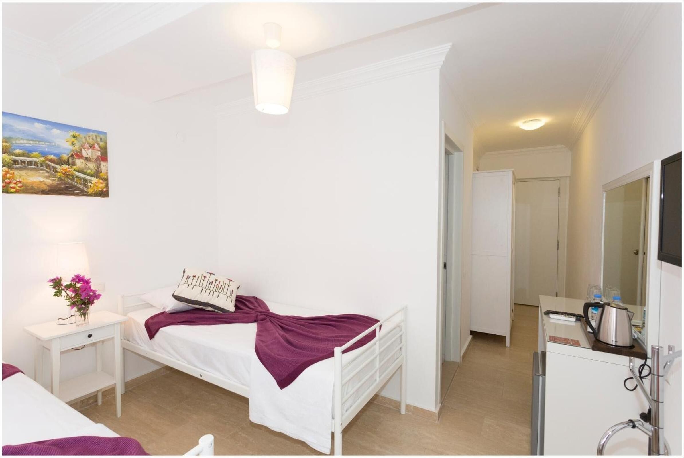 A bedroom with a bed, bedside table, lamp, and a painting on the wall.