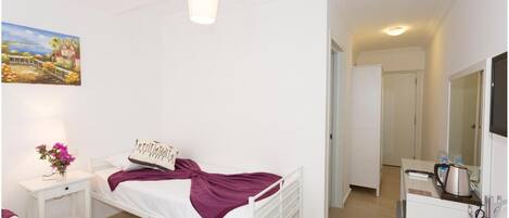 A bedroom with a bed, bedside table, lamp, and a painting on the wall.
