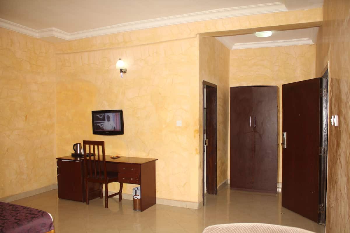 Ein Hotelzimmer mit Bett, Schreibtisch mit Stuhl, Fernseher und Kleiderschrank.