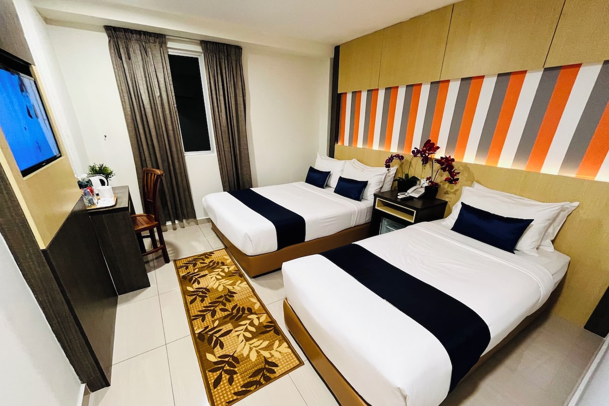Een hotelkamer met twee bedden, een bureau, een stoel, een televisie en een badkamer.