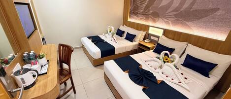 A hotel room with two beds, a desk with a chair, and a large wall-mounted artwork.
