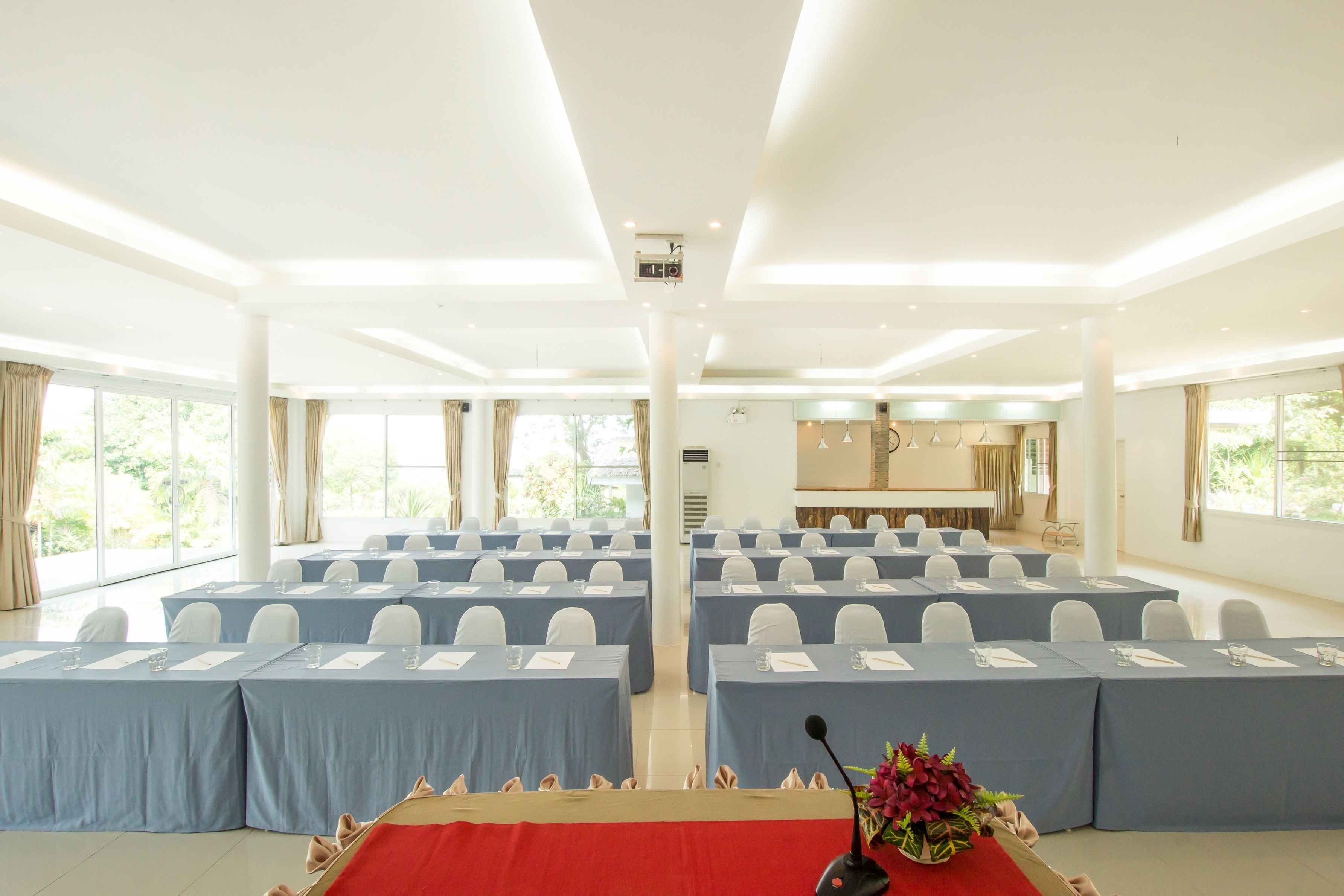 Un salón de conferencias con filas de mesas, sillas y un atril con micrófono.