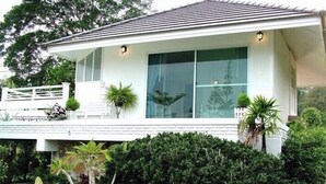 Una casa moderna con un amplio ventanal, paredes exteriores blancas y un jardín cuidado.