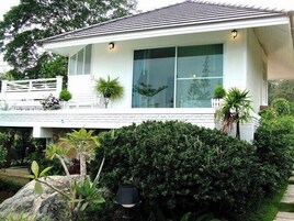 A modern house with a large glass window, white exterior walls, and a well-maintained garden.