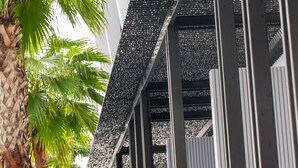 A modern building with a black facade and white vertical lines, featuring a palm tree in the foreground. - Chaweng Villawee (Koh Samui)