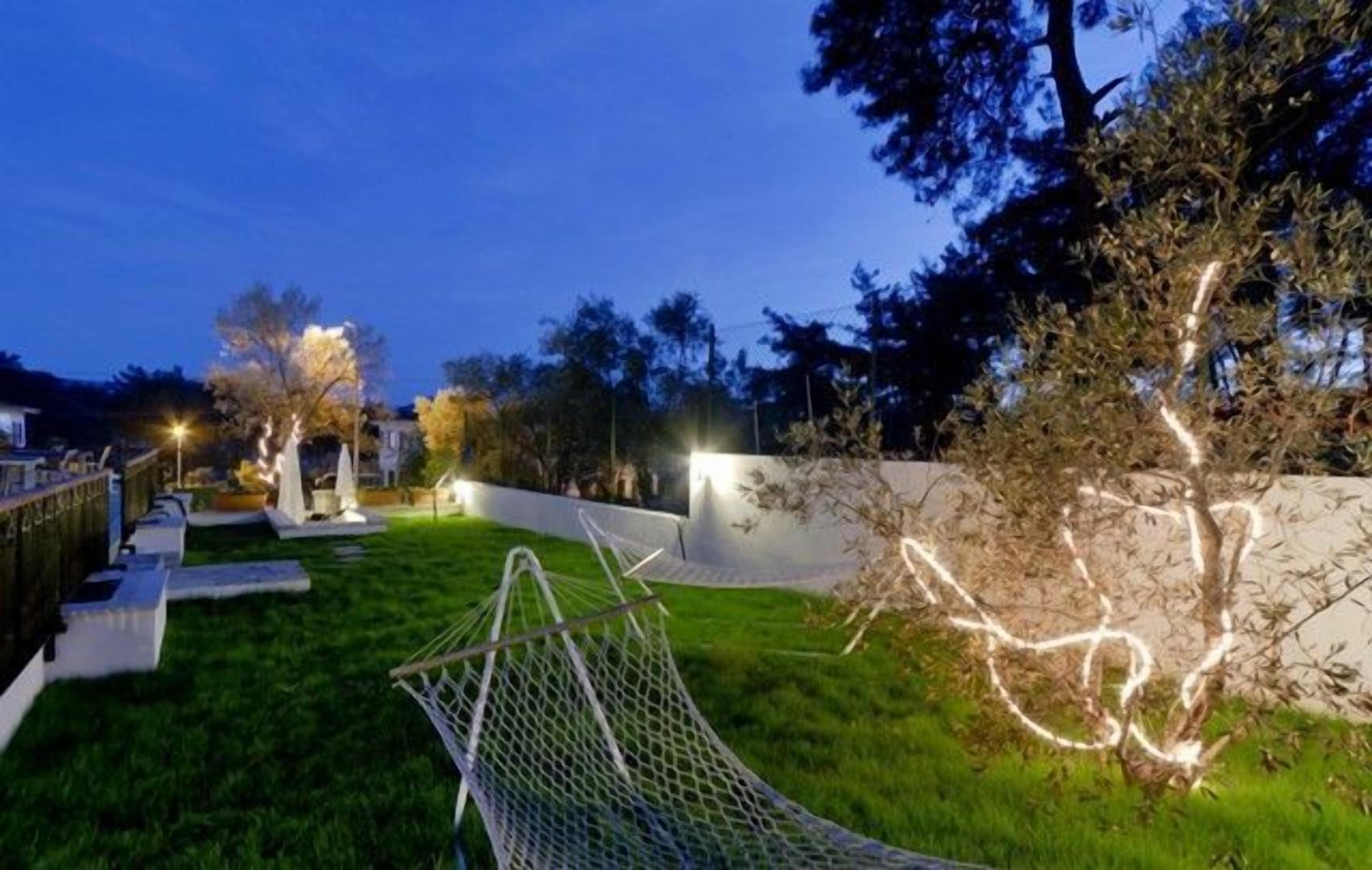 A landscaped backyard with a hammock, a white wall, and trees.