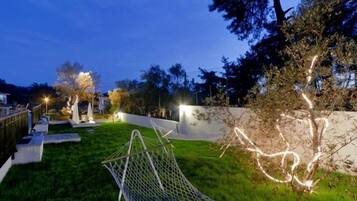 A landscaped backyard with a hammock, a white wall, and trees.