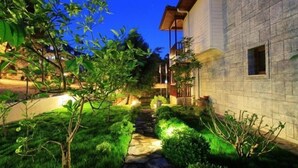 A stone building with a stone pathway leading to a wooden deck. - Summer Otel (Ula)