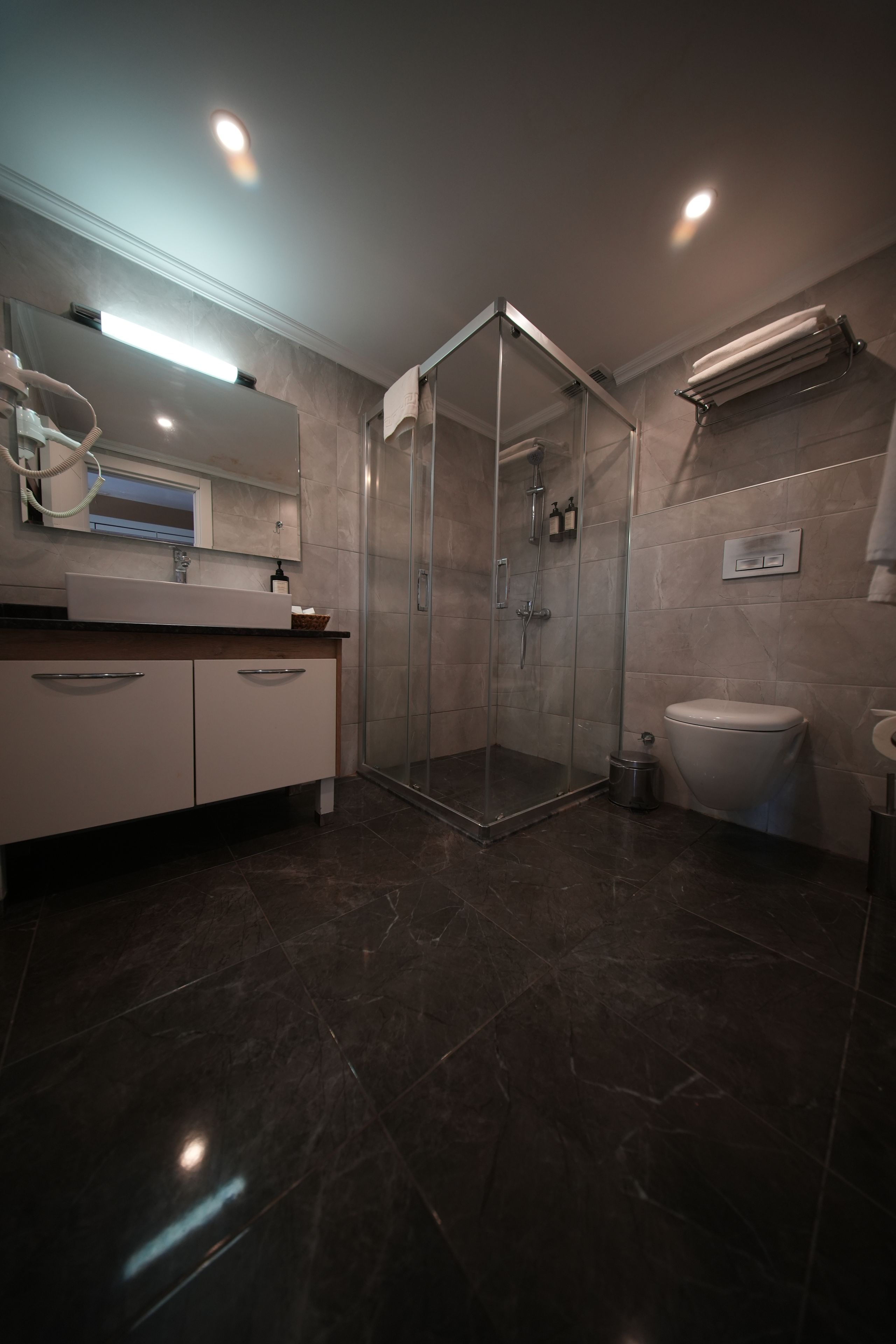 Un baño moderno con ducha de vidrio, inodoro y lavamanos con espejo.