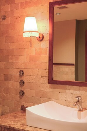 A bathroom with a white sink, a mirror, and a wall-mounted light fixture.