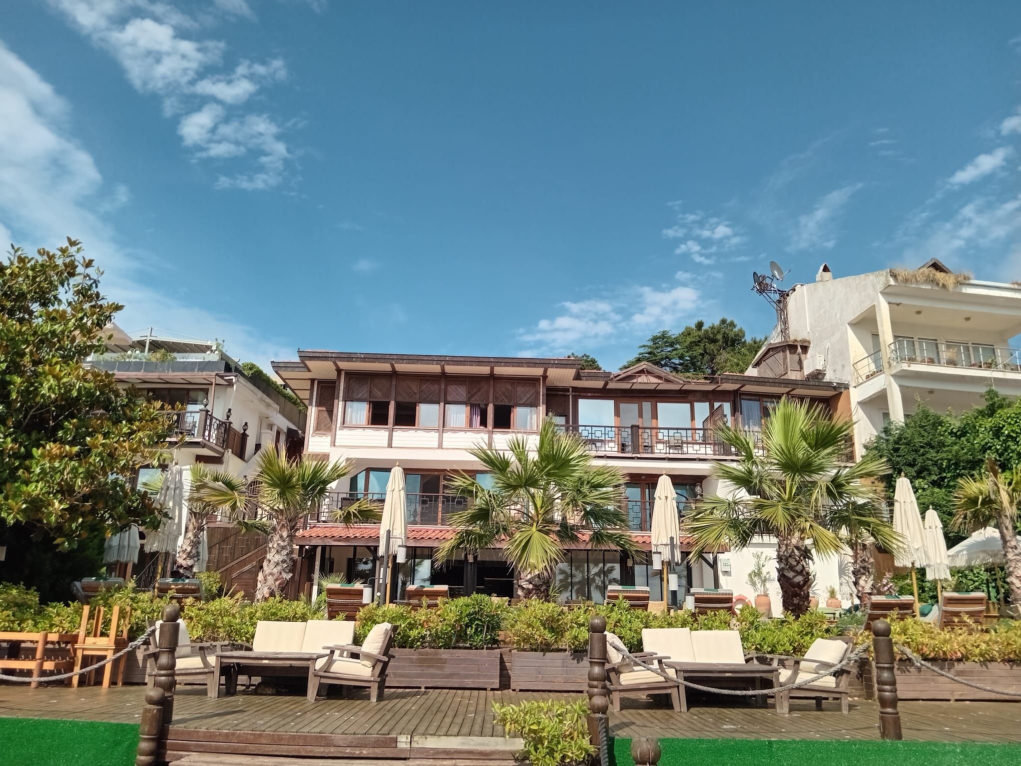 Un hotel de varios pisos con mesas al aire libre y una zona de piscina.