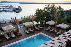 Una piscina al aire libre, sombrillas, sillones reclinables de piscina