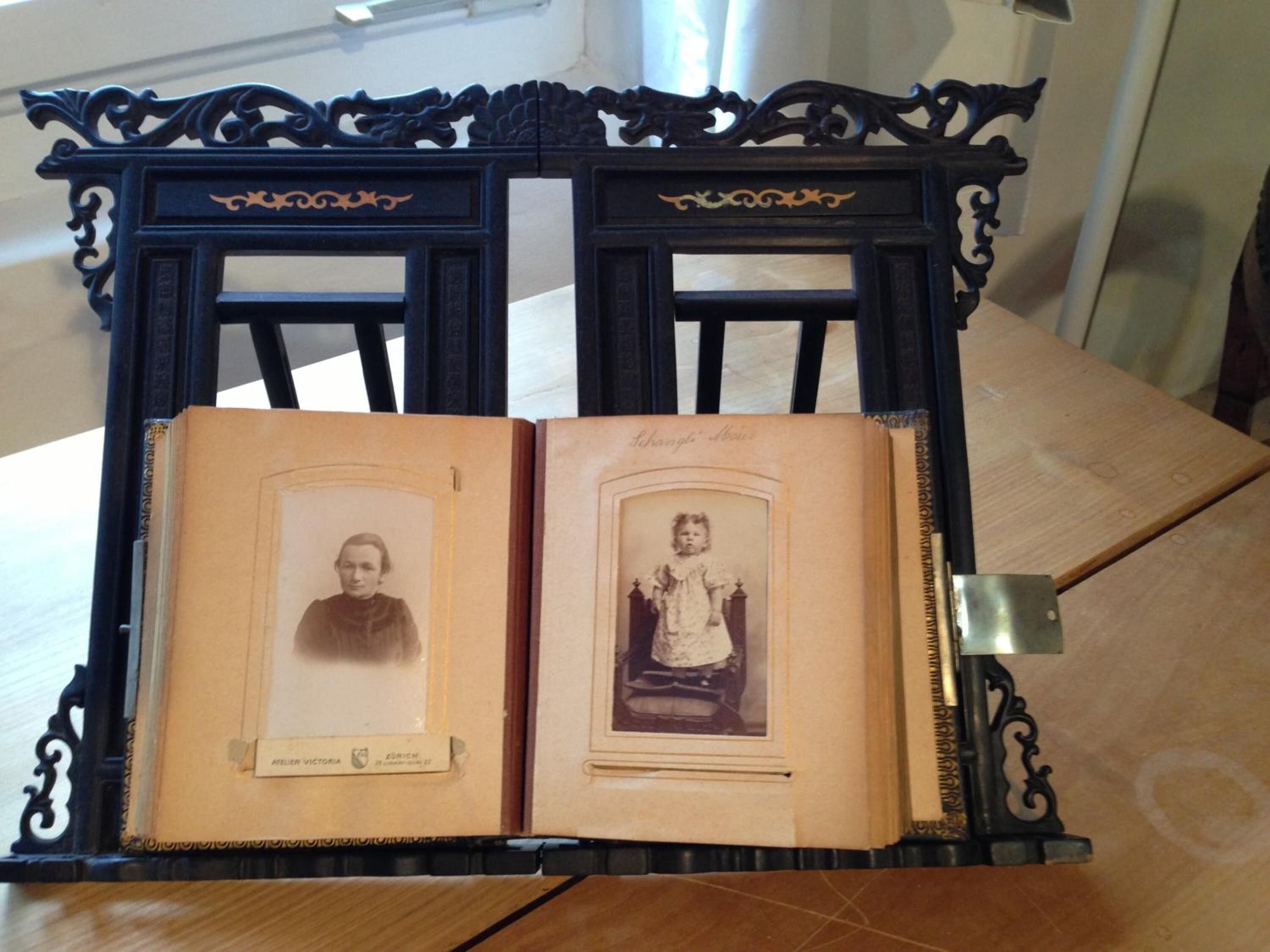 An open book with two framed photographs on a wooden table.