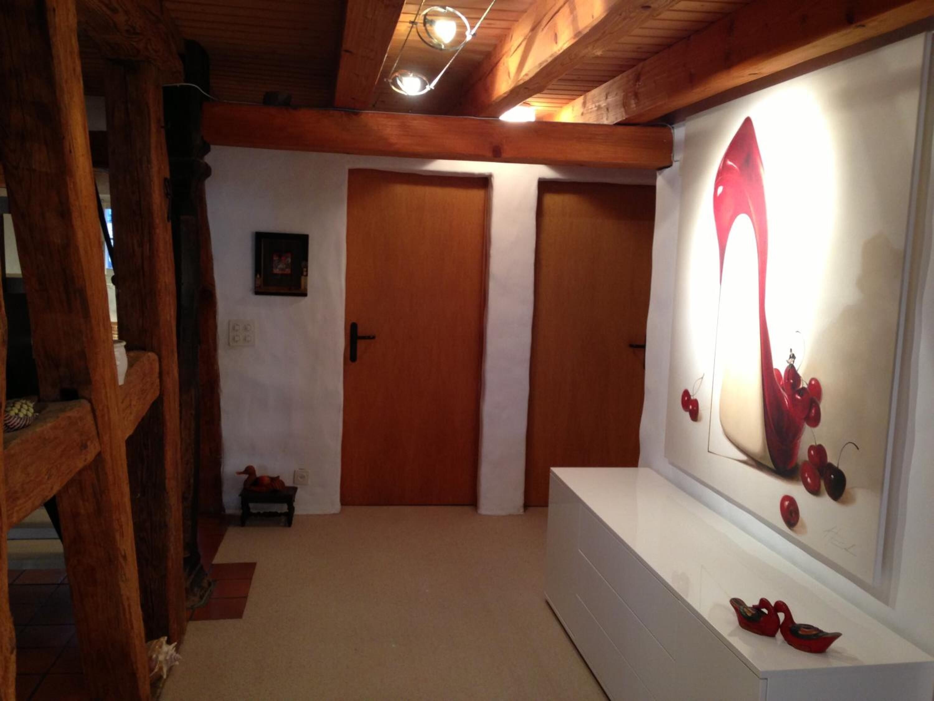 Un pasillo con vigas de madera, un banco blanco y una obra de arte colgada en la pared.