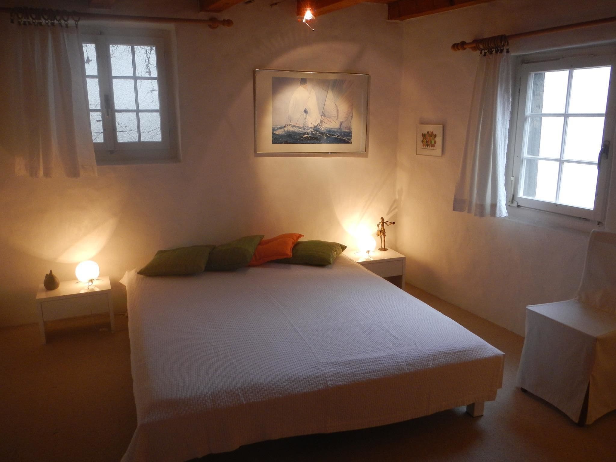 Une chambre à coucher comprenant un lit, deux tables de chevet, une commode, une chaise et une fenêtre.