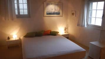 Une chambre à coucher comprenant un lit, deux tables de chevet, une commode, une chaise et une fenêtre.