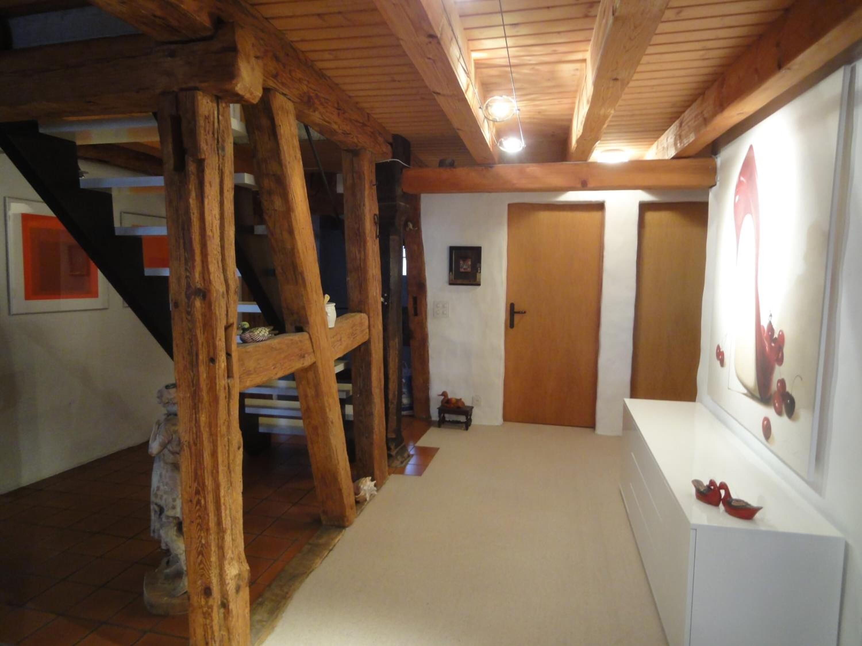 Un interior de madera con una escalera, una puerta y un cuadro en la pared.