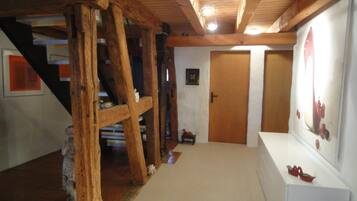 Un interior de madera con una escalera, una puerta y un cuadro en la pared.