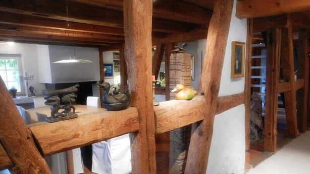 Un interior rústico con vigas de madera a la vista, una zona de cocina y una mesa de comedor con adornos.