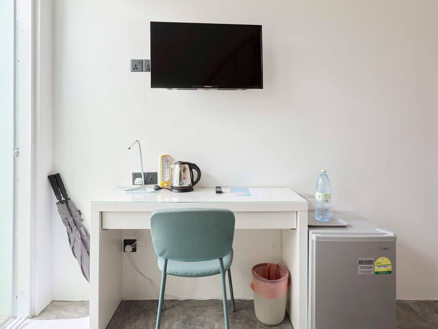 Een compact, modern kantoor met een bureau, stoel, televisie, waterkoker en een minibar.