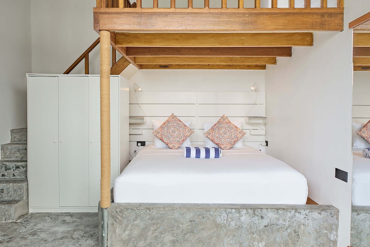 A bedroom with a bunk bed, a wooden staircase, a white wardrobe, and a cat tree.