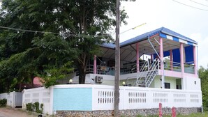 A two-story building with a blue roof and white walls, featuring a staircase on the second floor. - Chomlay Restaurant & Room for Rent (Rayong)