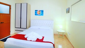 A hotel room with a bed, a wardrobe, a painting, a nightstand, and a lamp.