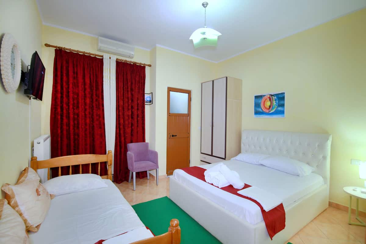 Habitación de hotel con dos camas, una silla, un armario y un cuadro en la pared.
