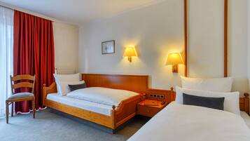 Ein Hotelzimmer mit einem hölzernen Bett, einem Sessel, zwei Nachttischen und zwei Wandleuchten.