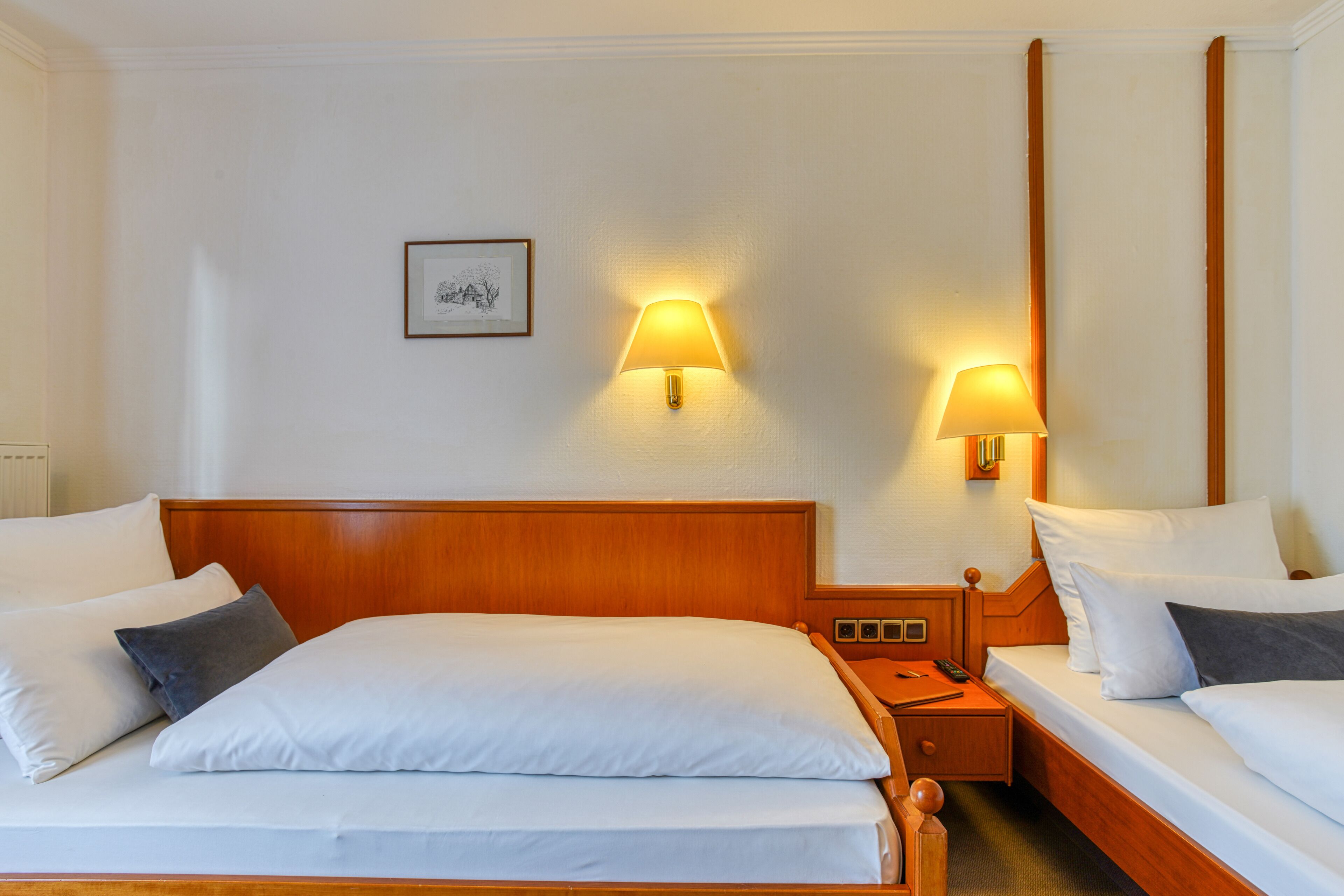 Una habitación de hotel con una cama grande, dos mesitas de noche y dos lámparas de pared.