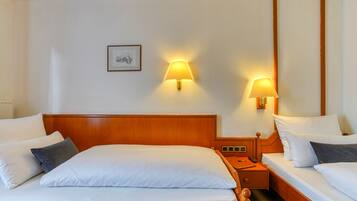 Una habitación de hotel con una cama grande, dos mesitas de noche y dos lámparas de pared.