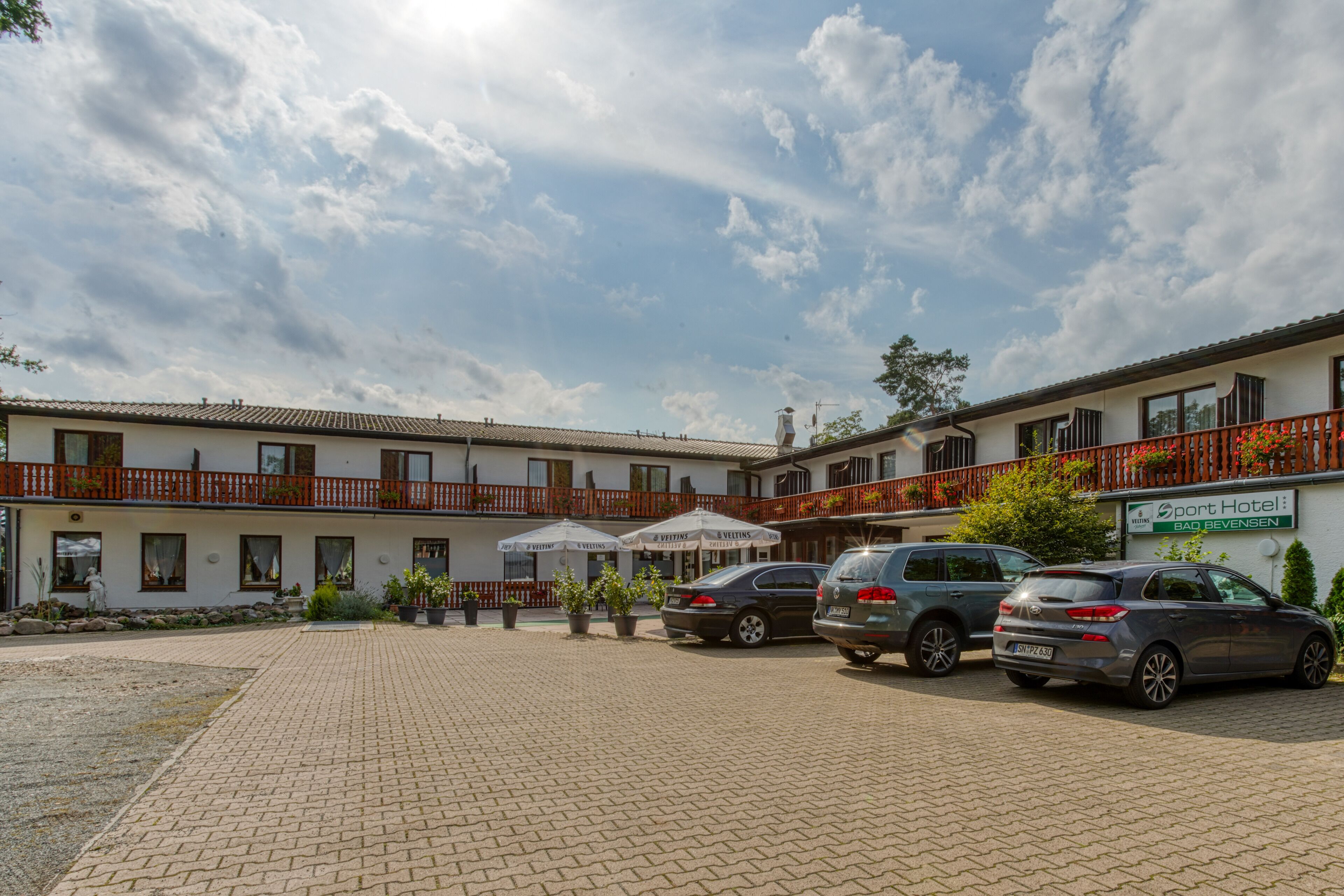 Un hôtel doté d’une cour dallée, de sièges en plein air et d’une enseigne indiquant « Port Hotel : Bad Bevensen ».