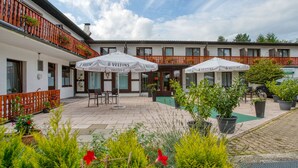 A courtyard with outdoor seating, potted plants, and umbrellas. - Sport Hotel Bad Bevensen (Bad Bevensen)
