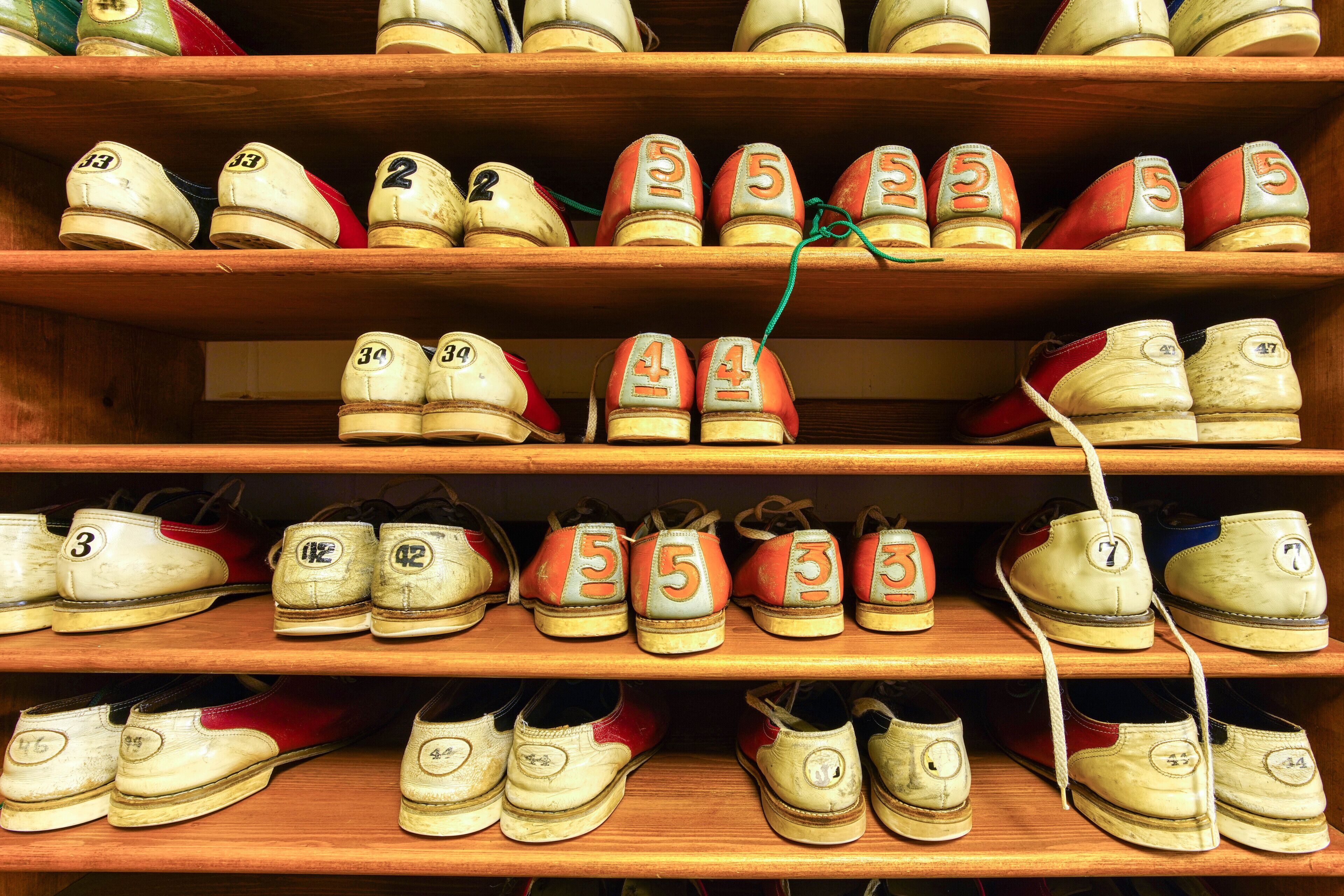 A collection of vintage sports shoes on wooden shelves.