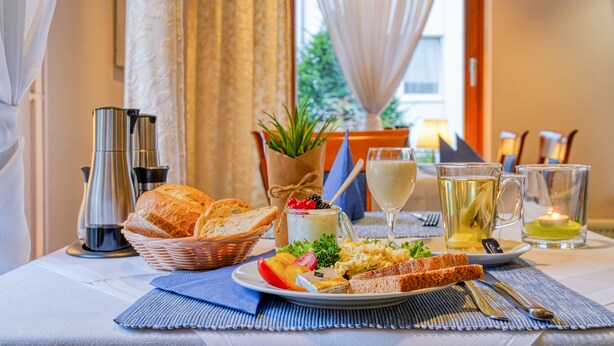 A breakfast setting with bread, fruit, cheese, and beverages on a table. - Sport Hotel Bad Bevensen (Bad Bevensen)