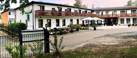 Un hotel con patio, mobiliario exterior y jardín cercado.