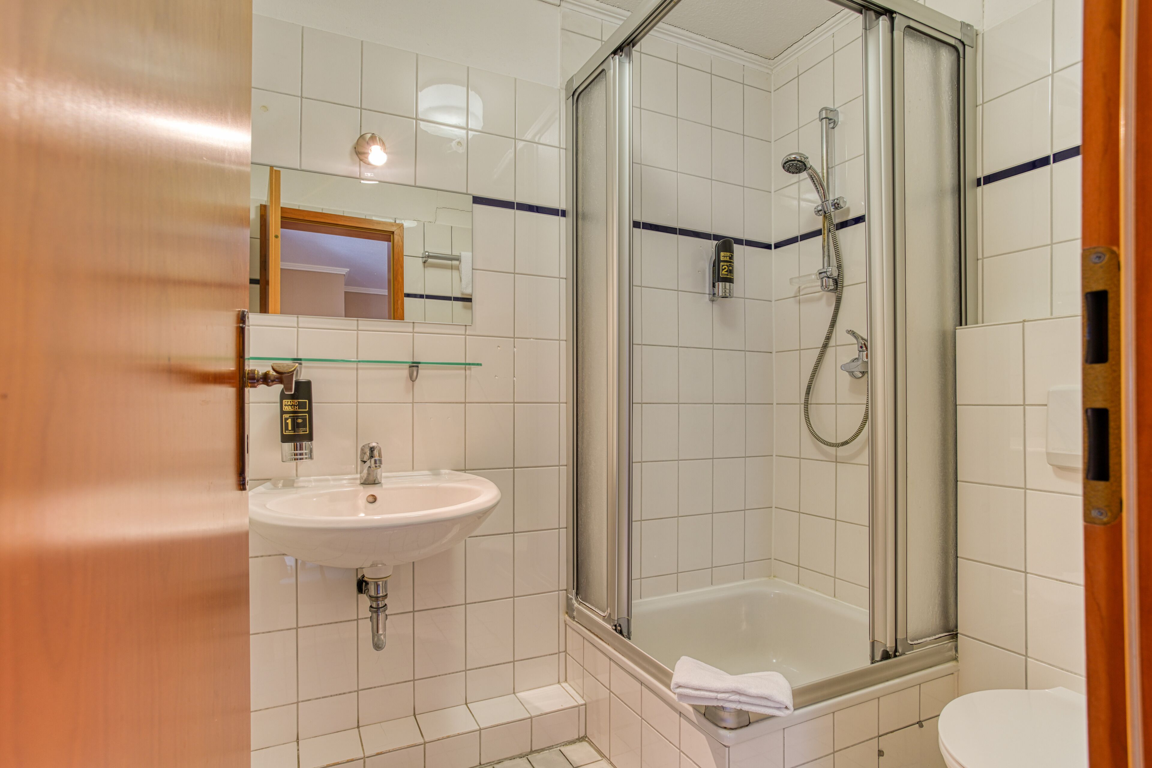 A bathroom with a glass-enclosed shower, a sink, and a toilet.