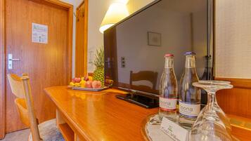 A wooden table with a fruit tray, two bottles of Loona wine, and a glass on a tray.