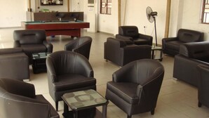 Un vaste espace de détente avec de nombreux fauteuils et canapés en cuir disposés autour d’une table de billard.
