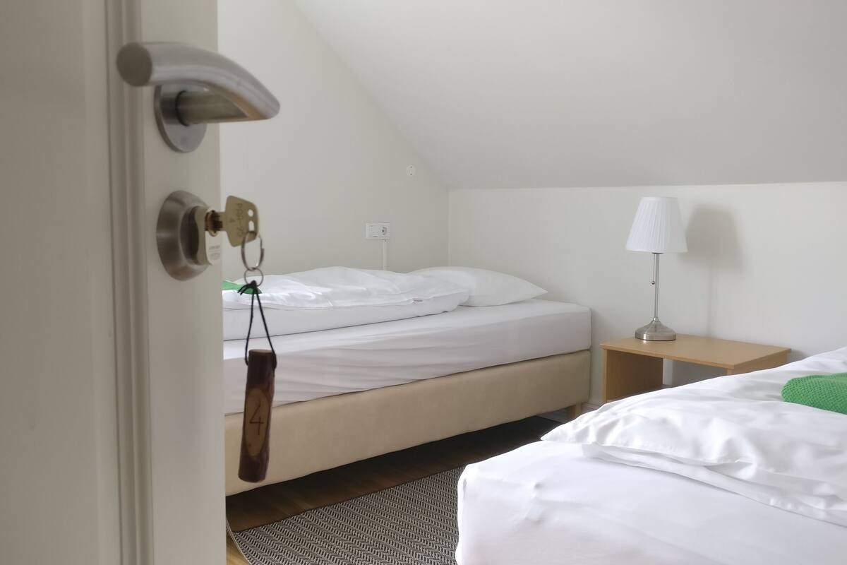 A bedroom with a single bed, a nightstand, a lamp, and a door with a key lock.