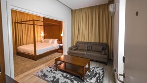 A hotel room with a four-poster bed, a sofa, a coffee table, and a large window with curtains. - Vanern Residence (Abuja)