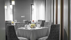 A dining area with a round table set for four, patterned chairs, and a vase of yellow flowers. - Vanern Residence (Abuja)
