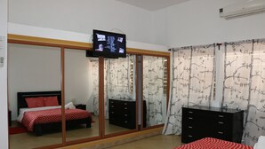 A bedroom with a bed, a TV mounted on the wall, a wardrobe, and a dresser. - SIS Hotel (Luanda)