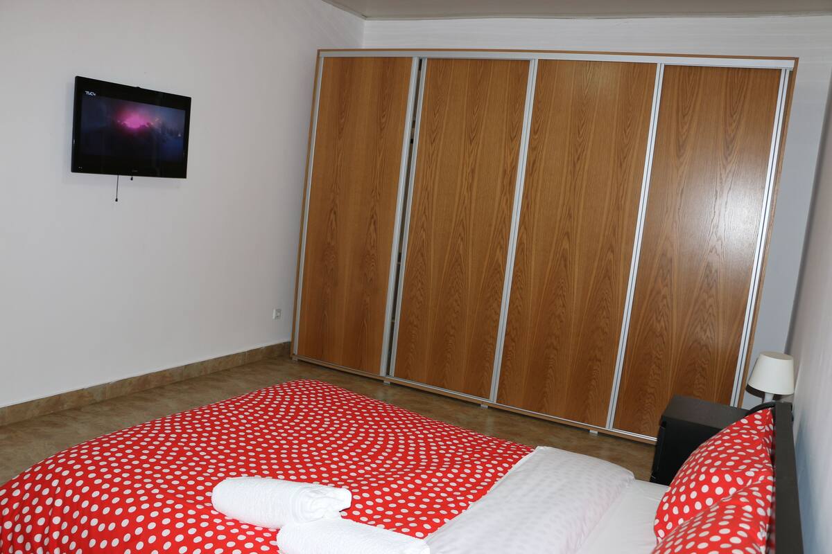 Une chambre d’hôtel avec un lit, une télévision et une armoire.